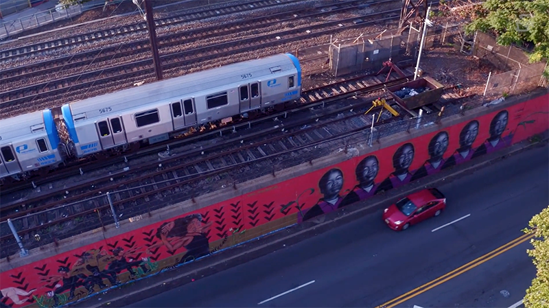 Aerial shot of art mural next to elevated Path train in Newark 