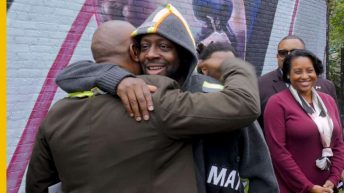 wyclef jean hugging a man, wyclef mural, wyclef, newark, upgraded, ras baraka