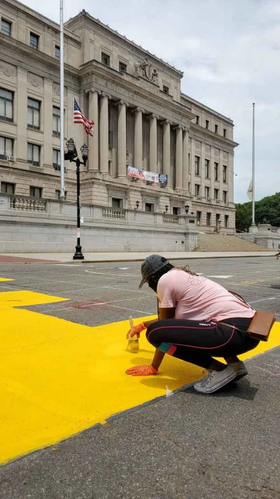Volunteer painting new street mural in Downtown Newark